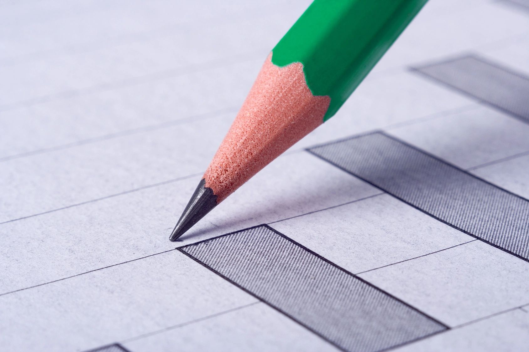 A green pencil marking checkboxes on lined paper.